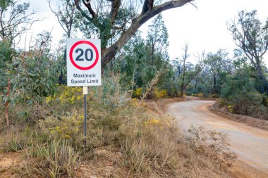 Avustralya 'nın Yeni Güney Galler bölgesindeki Mavi Dağlar' ın ücra bir köşesindeki dar toprak yolda saatte 20 km hızla giden yol işaretinin fotoğrafı..