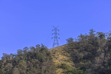 Photograph of a large electricity Transmission Tower on a grassy hill against a bright blue sky in regional Australia. clipart