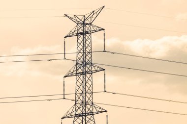 Avustralya 'da turuncu bir günbatımı gökyüzüne karşı bir elektrik iletim kulesinin üst kısmının fotoğrafı..