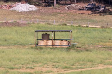 Avustralya 'nın Yeni Güney Galler bölgesindeki bir çim tarlasında düzgünce istiflenmiş saman balyalarının bulunduğu huzurlu kırsal bir manzaranın fotoğrafı..