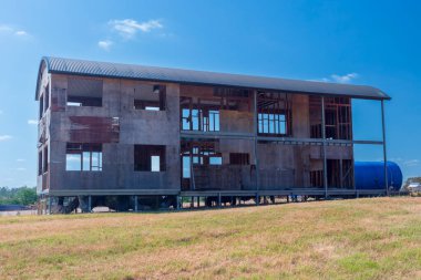 Avustralya 'da, parlak mavi bir gökyüzünün altında, yeşil bir çayırda harabeler içinde eski ve terk edilmiş çok katlı bir evin fotoğrafı..