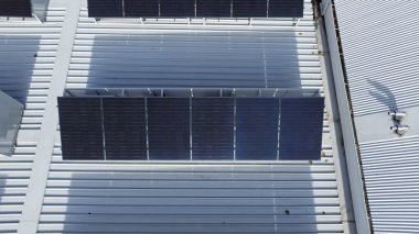 Bir ticari binanın çatısındaki güneş panelleri dizisinin insansız hava aracı fotoğrafı..