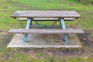 Aile büyüklüğünde ahşap ve çelik piknik masasının büyük bir halka açık kamp tesisinde yeterli oturma yeri olan sabit bir fotoğrafının çekilmesi..