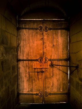 Taş duvarlara gömülü metal elementlerle güçlendirilmiş eski ahşap kapılar.