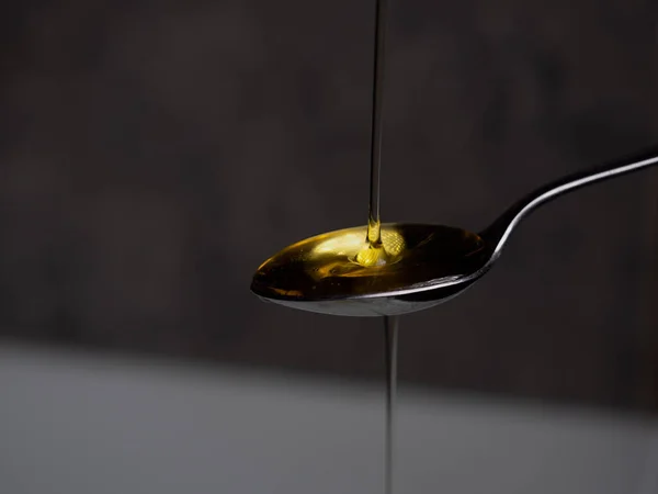 olive oil pouring on a spoon on a blurred background
