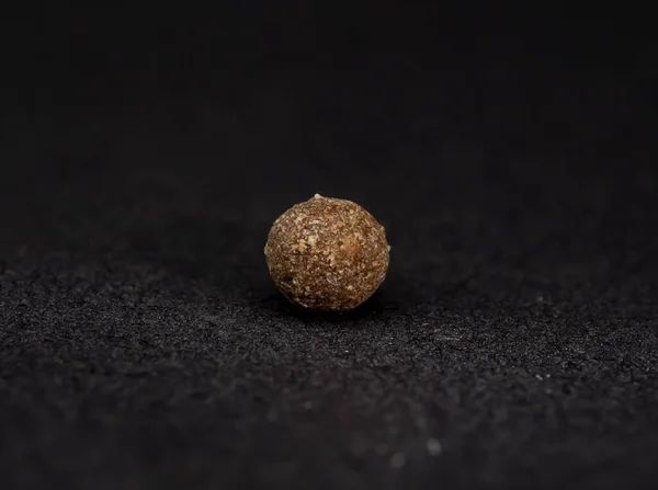 granule - a product with vitamins in the shape of a ball, a single granule macro photo, black background, a lot of details