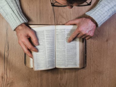 Caen, France 2023. Man reading an old book top view, wooden table