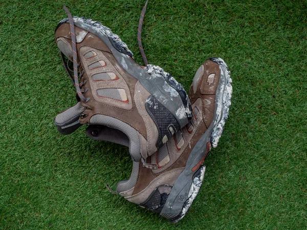 Caen, France 2023. dirty mountaineering boots lying on the green grass