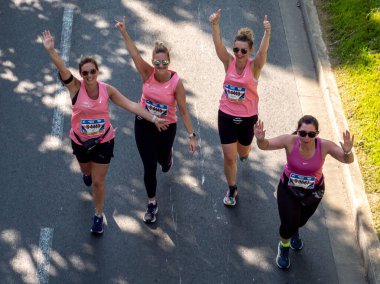 Caen, France Normandy June 4, 2023 happy women in pink t-shirts running Half Liberte Marathon in a group of Caen athletes, top view clipart