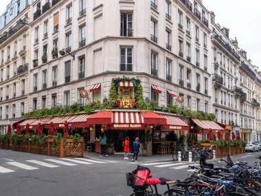 Paris, Fransa, 19 Nisan 2024: Turistler Paris Brasserie Martin restoranını ziyaret ediyor, kırmızı renkli ve çiçek desenli, sokakta duran bisikletleri, binanın önündeki insanları, EnrouteFrance