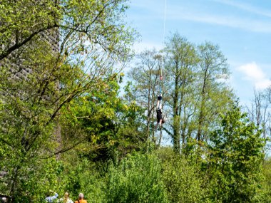 Clecy, Normandiya, Fransa, 10 Mayıs 2024. Kuzey Normandiya 'da, Cleacy' de bir bungee kordonuna atlamak, bir kişi ipin üzerinde baş aşağı atlamak, arka planda mavi gökyüzünde