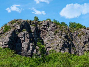 Cleacy 'deki dağlar Normandiya' da, doğal kayalar, arka planda yeşillik, bulutlu mavi gökyüzü.