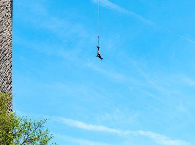 Clecy, Normandiya, Fransa, 10 Mayıs 2024. Kuzey Normandiya 'da, Cleacy' de bir bungee kordonuna atlamak, bir kişi ipin üzerinde baş aşağı atlamak, arka planda mavi gökyüzünde