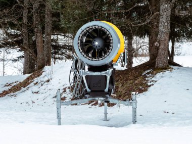 Chamonix, Fransa 23 Ocak 2025. Ağaçlarla çevrili karla kaplı bir arazide bir kar silahı duruyor. Bu cihaz kayak pistlerinde kar üretmek için yapay olarak kullanılır.