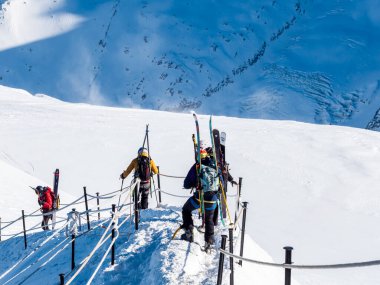 Chamonix-Mont-Blanc, Fransa, 21 Ocak 2025. Sırt çantalı ve paraşütlü insanlar Aiguille du Midi 'nin dik, karla kaplı yamacından paraşütle atlamak için inerler.
