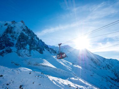 Chamonix, Fransa 19 Ocak 2025. Arkadaki dağlarda Gondol tipi dağ kaldırma kabini ve güneş, Chamonix Alps France