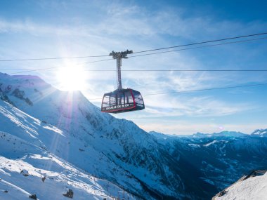 Chamonix, Fransa 19 Ocak 2025. Arkadaki dağlarda Gondol tipi dağ kaldırma kabini ve güneş, Chamonix Alps France