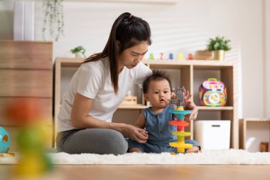 Asian mom teaching baby boy learning and playing toys for development skill at home or nursery room. Happiness mother and baby spending time together at warmth place. Good moment with mom and baby