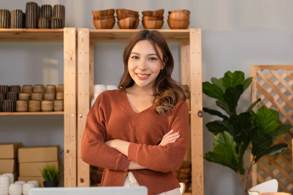 Happy Asian young business owner flower vases store standing cross arms smile and looking at camera. Confident female entrepreneur surrounded by beautiful flower vases at home