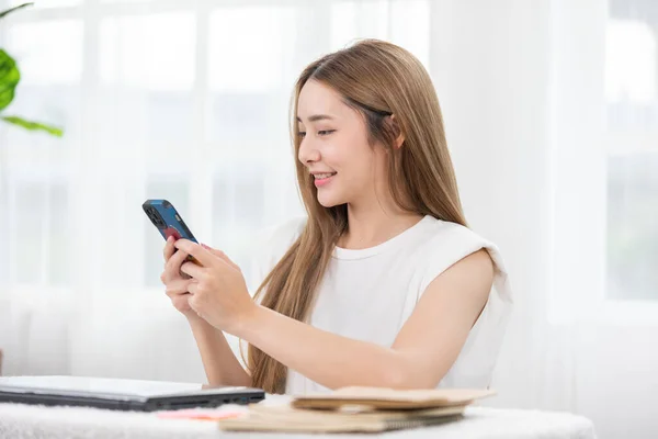 スマートフォンサーフィンインターネットを利用した幸せなアジアの若い女性の笑顔と自宅でソーシャルメディアやオンラインショッピングでお楽しみください 携帯電話の楽しさと幸福を見てかわいい女性の現代的な健康寿命 — ストック写真