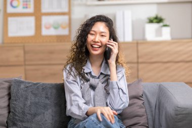 Asyalı genç kadın telefona cevap verir ve olumlu ve mutlu bir şekilde konuşur. Akıllı telefon tebessümü ile konuşan, iyi haberlerle ve evde güzel anlarla aldatan, duygusal bir kadın.