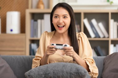 Oyun oynarken joystick kullanan genç bir kadın. Kadın sert bir maçta maçı kazanıyor, ekrana bakıyor. Heyecanlı kız kazanan çevrimiçi oyun oynuyor