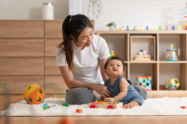 Asian mom teaching baby boy learning and playing toys for development skill at home or nursery room. Happiness mother and baby spending time together at warmth place. Good moment with mom and baby