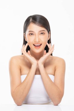 Güzel Asyalı kadın yumuşak yanaklı gülüşüne dokunuyor temiz ve taze tenli mutlu ve neşeli, olumlu duygusal, beyaz arka planda soyutlanmış, güzellik kozmetiği ve kaplıca yüz bakımı kavramı