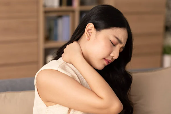 An Asian woman  do self massage at her neck and shoulders. She has got back and pain on her muscles. Massage could help her release her pain but the best way is to asking the advices from the doctor.