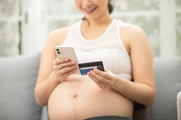 自宅でクレジットカードのオンラインショッピングを使用して幸せな妊婦 携帯電話でインターネットオンラインストアから赤ちゃんの服を購入する母親 妊娠ショッピングオンラインコンセプト — ストック写真