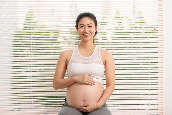 Счастливая Беременная Азиатка Сидит Кровати Гладит Свой Большой Живот Дома Лицензионные Стоковые Фото
