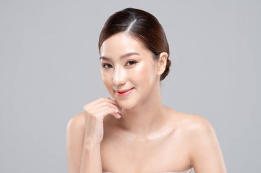 Güzel Asyalı kadın yumuşak yanaklı gülüşüne dokunuyor. Temiz ve taze tenli. Mutluluk ve neşe, olumlu duygusal, beyaz arka planda izole edilmiş.