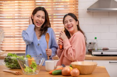 Birkaç LGBTQ aşığı mutfakta birlikte yemek pişiriyor gülümsüyor ve gülüyor. Mutluluk ve evde geçirilen hassas anlar. LGBTQ + Konsepti