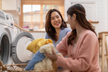 Birkaç LGBTQ aşığı birlikte çamaşır yıkıyor, gülümsüyor ve gülüyor. Mutluluk ve evde geçirilen hassas anlar. LGBTQ + Konsepti