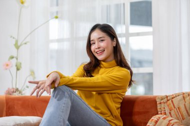 Güzel Asyalı genç kadın gülümsüyor ve neşeli. Kendine güvenen sevimli bayan kameraya bakıyor rahatla ve sağlıklı bir hayat yaşa. İyi bir an ve olumlu bir duygu. Mutlu kadın hayat kavramının tadını çıkarıyor.