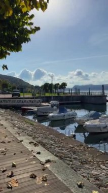 Rıhtımın sonbahar manzarası. Gölde dağlara bakan tekneler var. Küçük eski İtalyan kasabası Ranco, İtalya