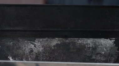 Kömür torbadan ızgaraya dökülüyor. Kara toz farklı yönlere uçuyor.