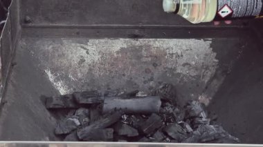 Izgara için kömürün üzerine yanıcı bir sıvı dökülüyor. Bir kadının eli, bir şişe likit tutar. Açık ateşte Pişirme için Hazırlanıyor.