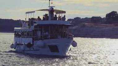 Bir Turist Gemisi Gün batımında Yavaşça Yelken Açar. Koyu yüzlü turistler gemide. Akdeniz 'de Aktif Tatil.