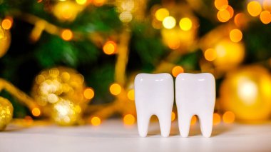 İki beyaz plastik diş modeli noelde bulanık arka planda duruyor. Diş hekimliği. Diş bakımı. Yeni yıl, Noel, Aziz Niklas Günü. Mesaj için yer var. Pankart