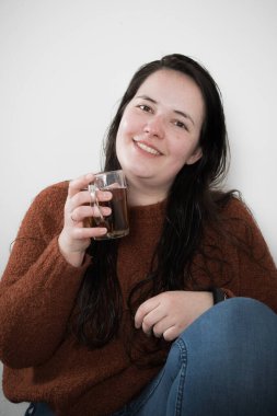 a woman with a red sweater is drinking tea