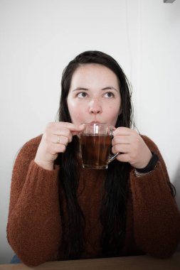 a woman in a black sweater with a cup of coffee