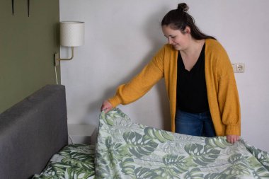 Kadın yatağını yapıyor.