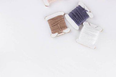 Skeins of cotton threads of different colors lie in a pile on a white background