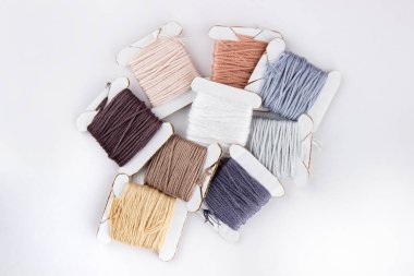 Skeins of cotton threads of different colors lie in a pile on a white background