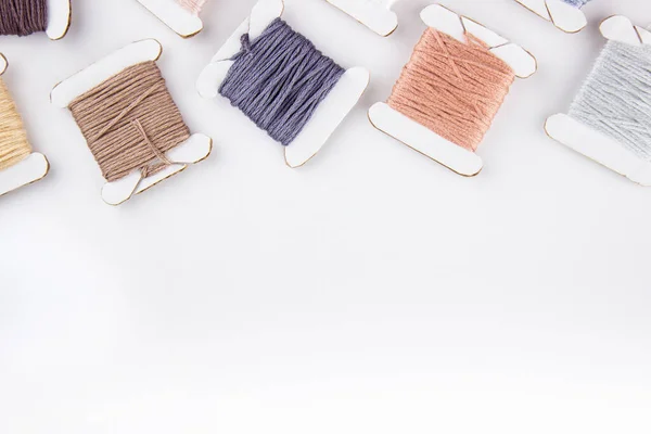 Skeins of cotton threads of different colors lie at the top of the frame on a white background