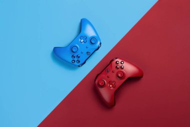 Mavi ve kırmızı arka planda iki Xbox oyun platformu yan yana uzanıyor.
