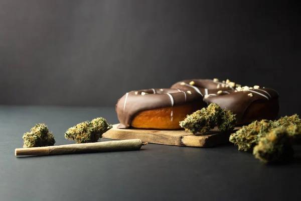 Ντόνατς Επικάλυψη Σοκολάτας Βρίσκονται Μαύρο Φόντο Δίπλα Μπουμπούκια Ιατρικής Μαριχουάνας — Φωτογραφία Αρχείου