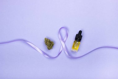 Epilepsi gününün sembolü mor bir kurdelenin kenarlarında kurumuş bir tıbbi marihuana tomurcuğu ve sarı cbd yağı özlü cam bir şişedir. Mor bir arka planda.