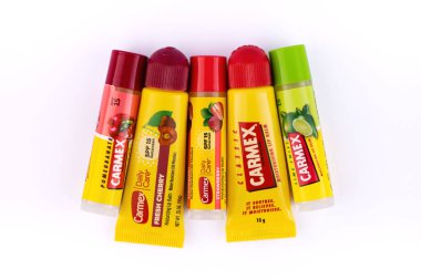 Beyaz arka planda Carmex markasından bir sürü farklı dudak kremi var. Limon, çilek, kiraz ve nar aromalı ve klasik.